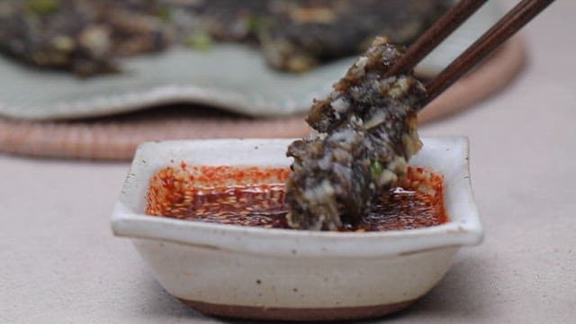 Eating laver pancakes dipped in soy sauce mixed with red pepper powder