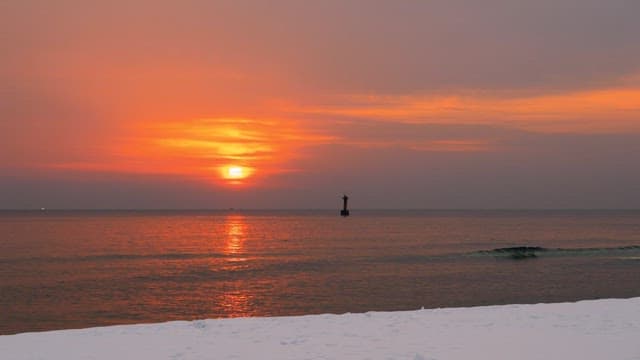 Person watching a sunset by the snowy beach