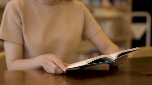 Person reading a book at a table