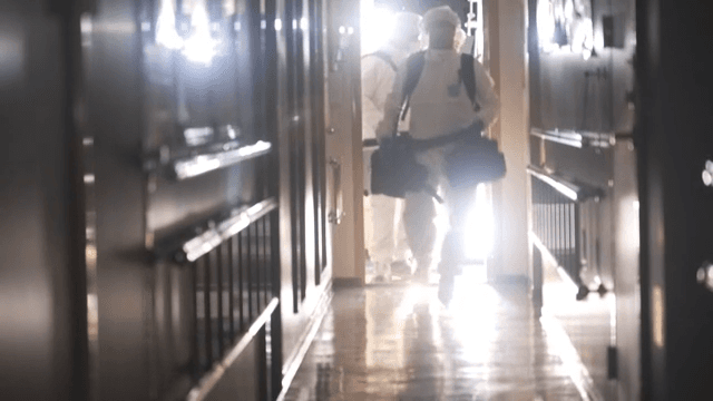 People in protective suits entering a hallway