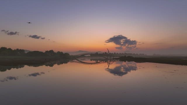 Serene river at sunset with a bridge