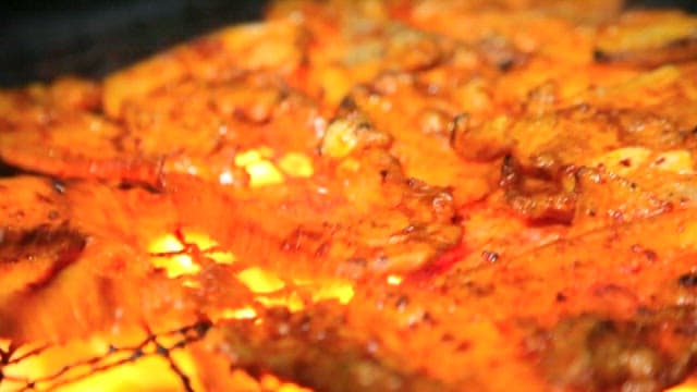 Charcoal-grilling pork belly over open flame