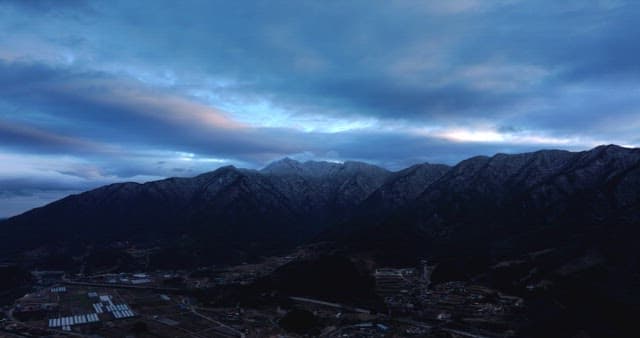 Snow-covered mountains under cloudy skies