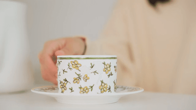 Woman drinking coffee from a teacup with flowers on it