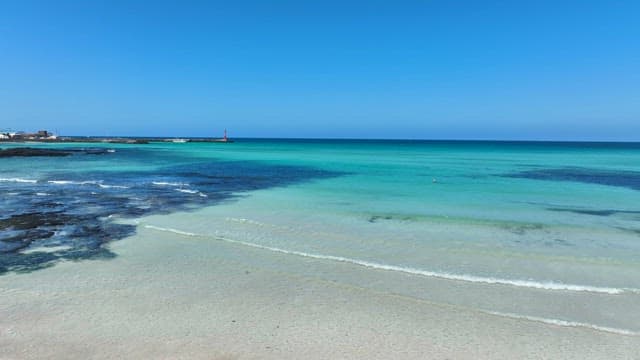 Clear turquoise sea with a distant lighthouse