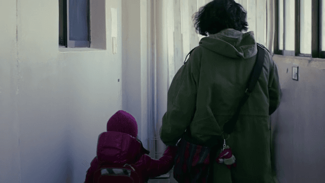 Parent and child walking down a corridor holding hands.