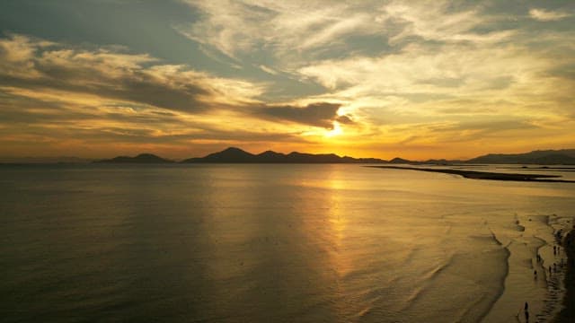 Serene beach at sunset with distant mountains