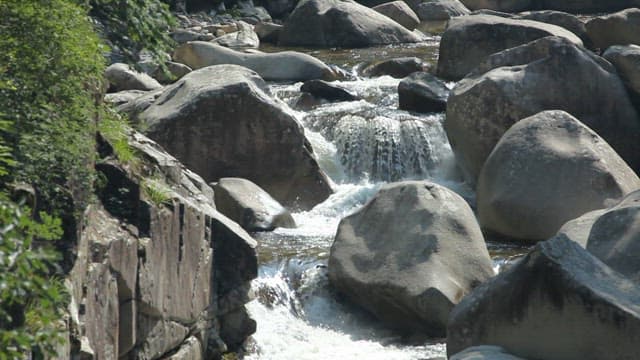 Cool water flowing through rocky valley on a sunny day