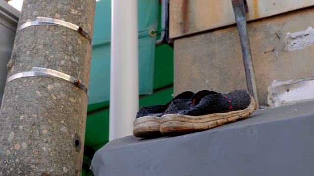 Old shoes abandoned next to a telephone pole