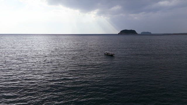 Boat on the calm sea with distant islands