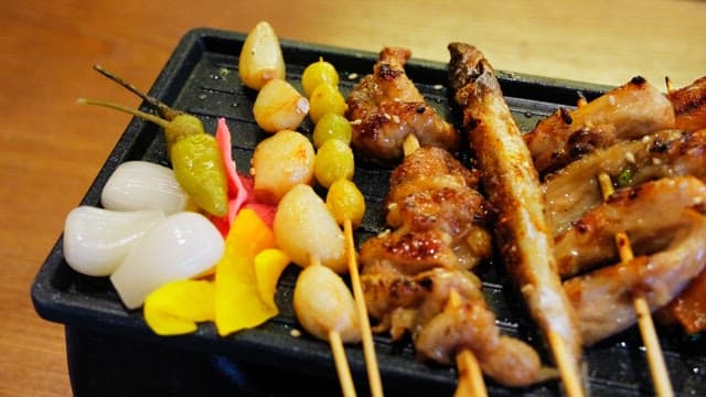 Various types of grilled skewers neatly arranged on an iron plate