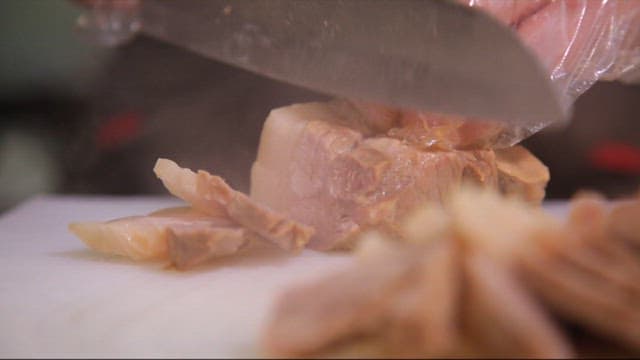Slicing boiled pork on a cutting board