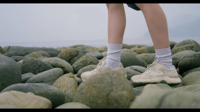 Person Walking on a Rocky Beach with Pebbles