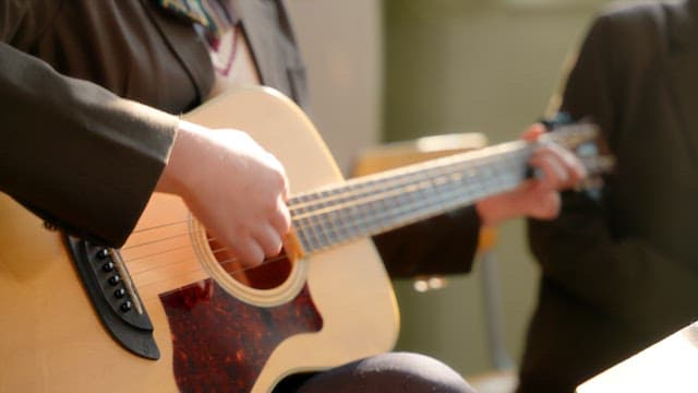 Student playing guitar in a classroom