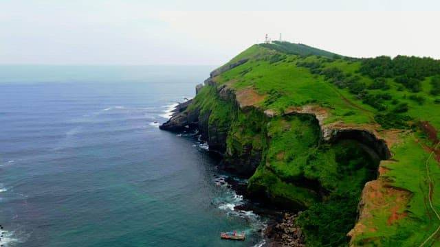 Coastal cliffs with green hills and a lighthouse