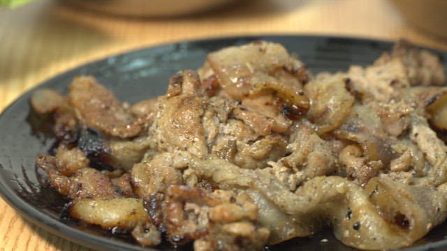 Grilled appetizing pork bulgogi being served on a black plate