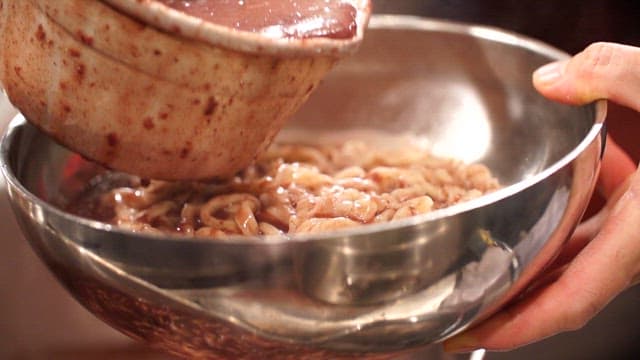 Pouring red bean porridge into a bowl with noodles
