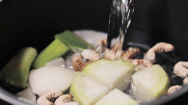 Pouring water into pot with vegetables and edible insects