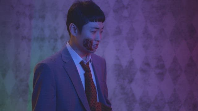 Man in suit rubbing his face in a dark room