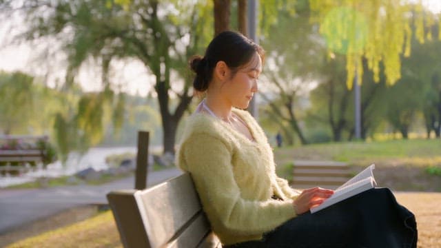 Woman reading a book on a park bench
