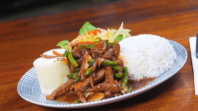 A plate of rice with stir-fried beef and vegetables