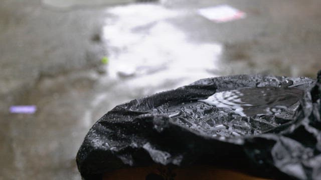 Puddle forming on a black plastic bag in rainy day