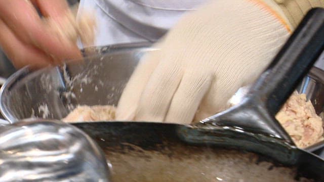 Putting meat mixture into hot oil in the kitchen