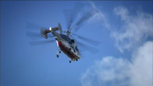 Helicopter Carrying Cargo Against Blue Sky