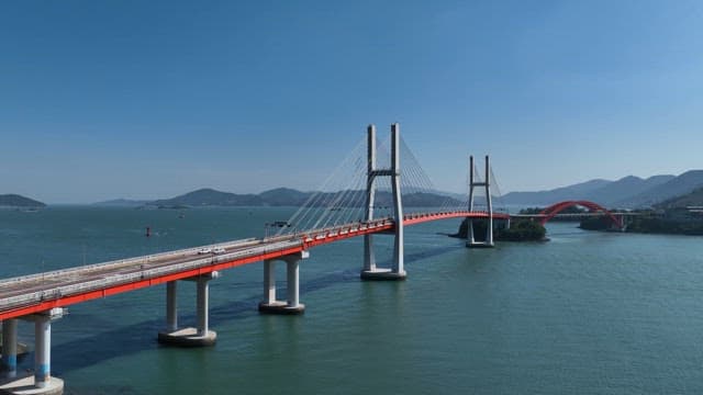 Red bridge spanning over a calm sea