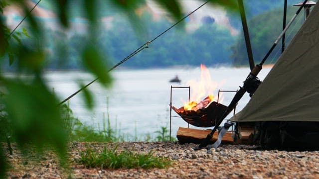 Campfire burning brightly with logs in the lakeside brazier at the evening