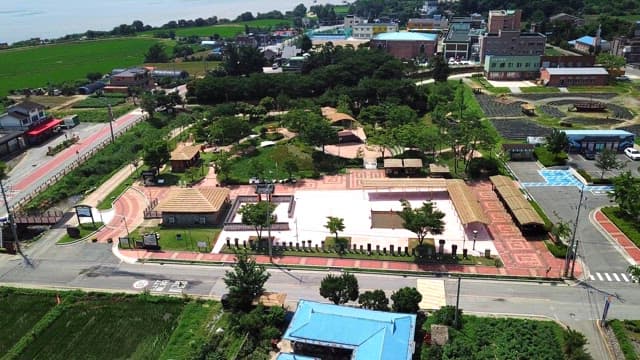 View of a small town surrounded by lush greenery and farmland on a bright sunny day