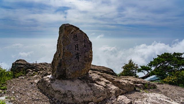 Inscribed stone atop a mountain with clouds