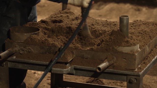 Workers shaping sand molds in a factory