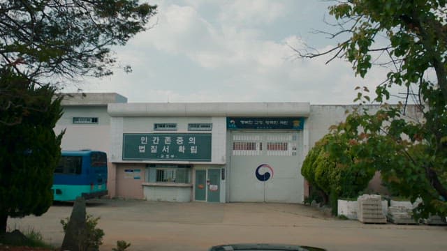 Prison exterior with a bus and a car parked outside