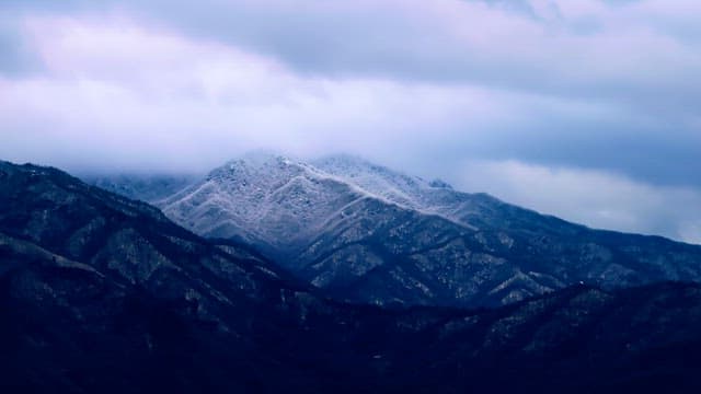 Snow-covered mountains under cloudy skies