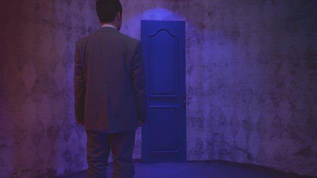 Man expressing his anger in front of a blue door under dark lighting