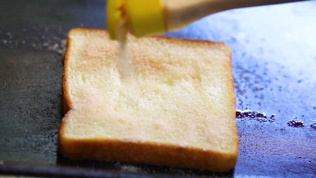 Scene where sugar is sprinkled on bread and various ingredients are added