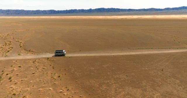 Van traveling through a vast desert