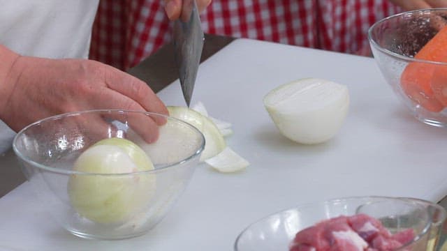 Cutting Onions with a Knife on a Cutting Board in the Kitchen
