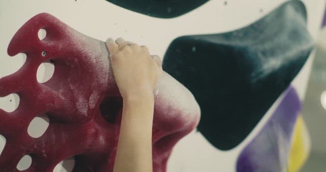 Hand holding a red hold on an indoor climbing site