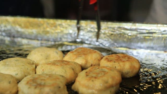 Griddlecake with sugar filling fried until golden brown in hot oil on an iron plate