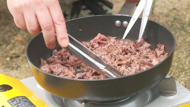 Cooking beef in a pan outdoors