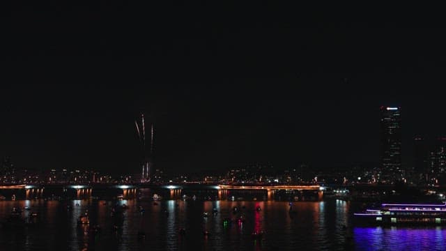 Fireworks over a city river at night
