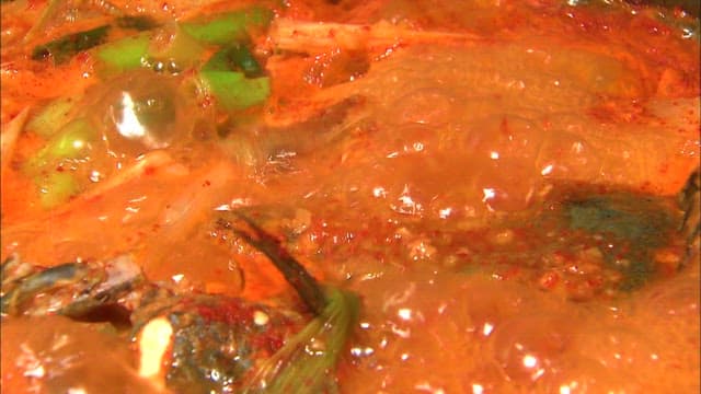 Scene of vegetables being added to boiling spicy fish stew
