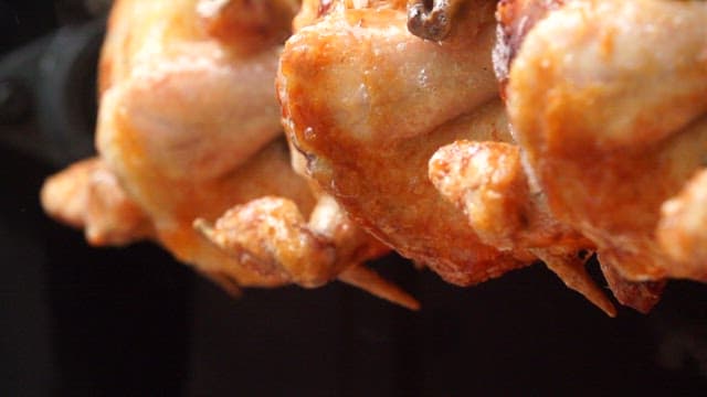 Wood-fired whole chicken roasting over open flames