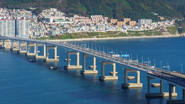 Day to night view of the bridge connecting the coastal city over the calm sea