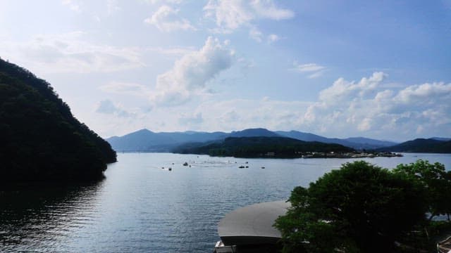 Boats sailing on a serene lake surrounded by lush green mountains