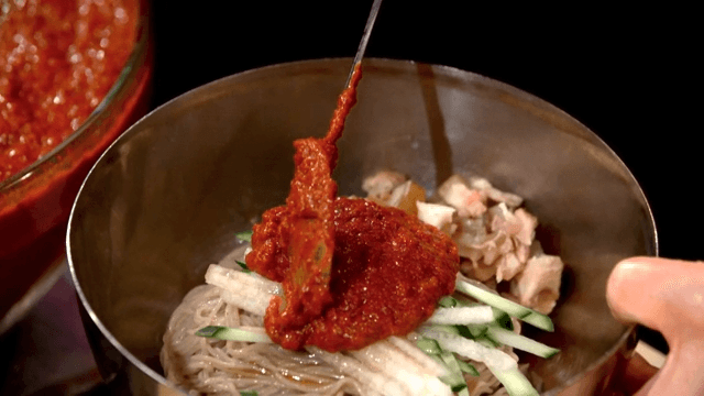 Adding seasoning sauce to Korean cold noodles