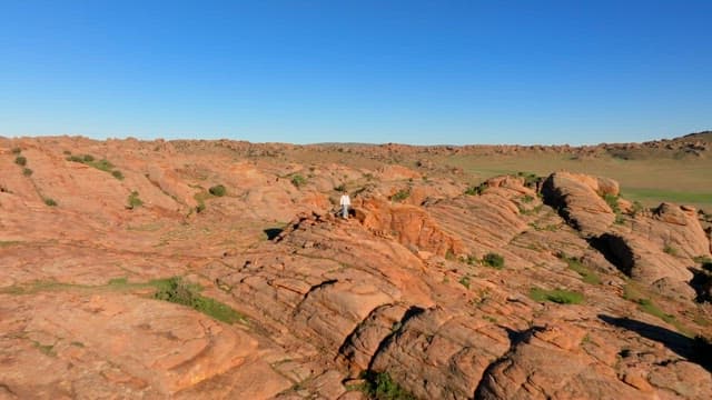 Person standing on rocky mountain under a clear blue sky