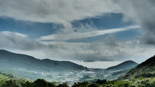 Mountains and valleys under a sky with drifting clouds